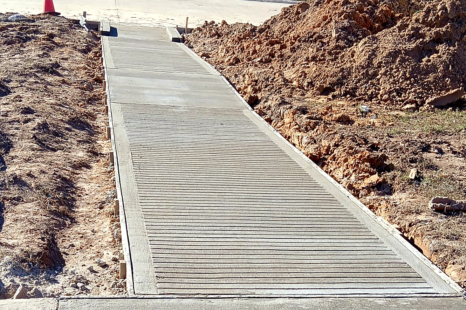 Concrete sidewalk approach with a horizontal broom finish running along a residential lot