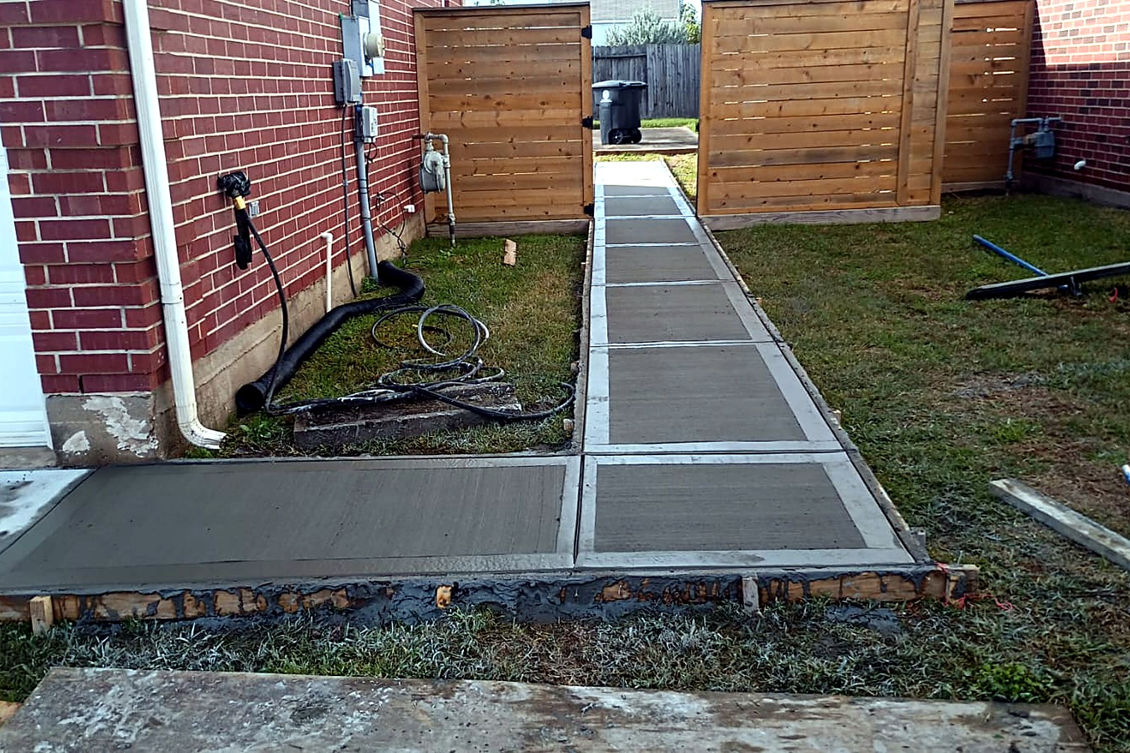 Long grey concrete side-yard walkway divided into even panels