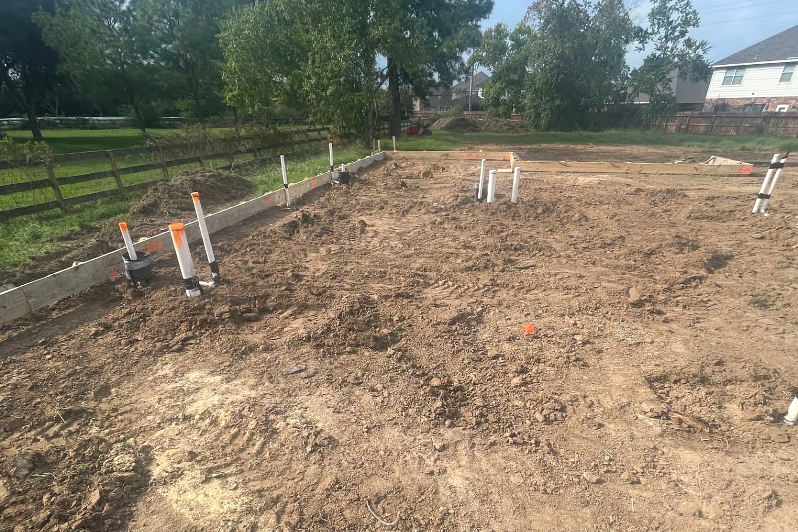 Foundation site prep with a formed perimeter beam and capped plumbing stub-outs along the property line
