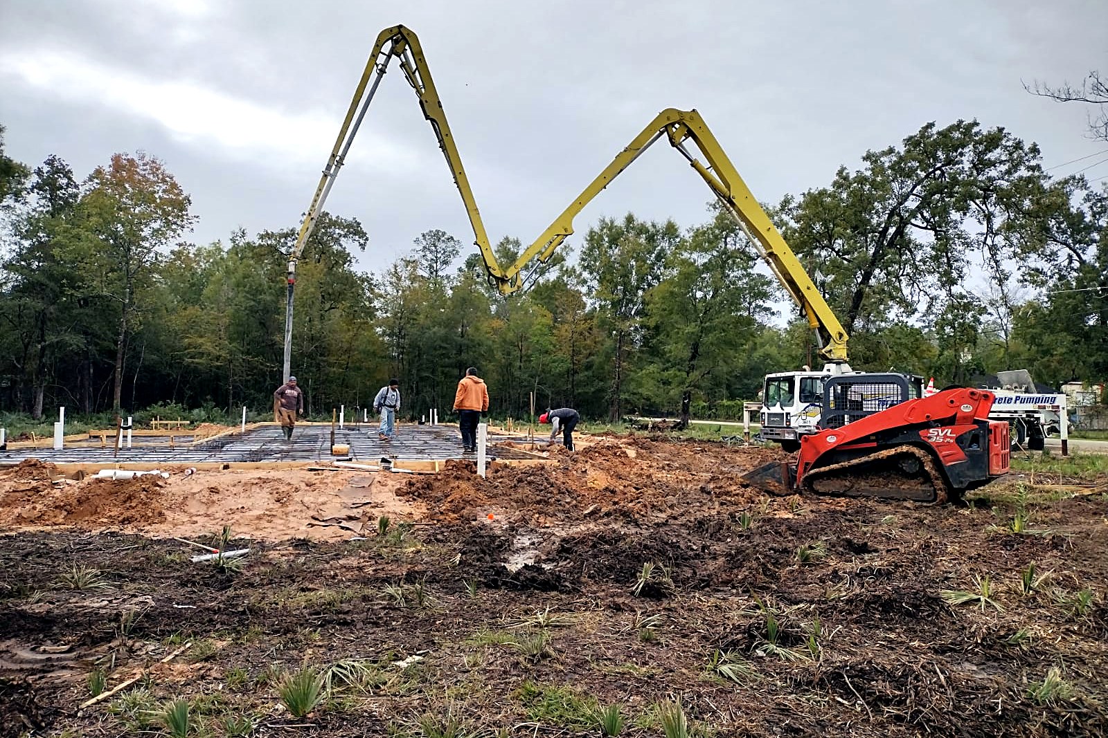 Concrete boom pump placing concrete across a large house foundation slab