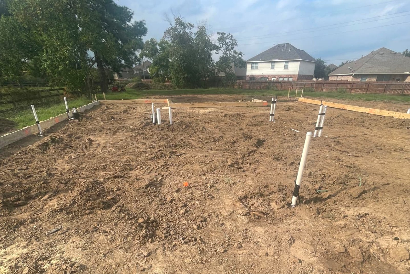 Graded building pad enclosed by foundation forms with plumbing stub-outs marked